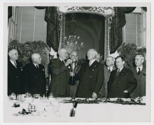 Men at center of large group pass trophy between themselves