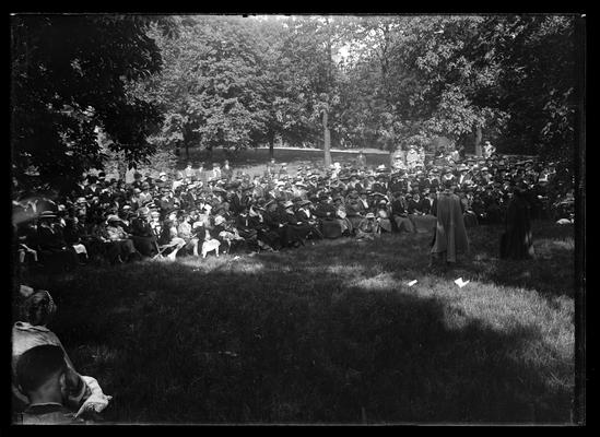 Pageant, crowd assembled on campus under trees, part of the audience