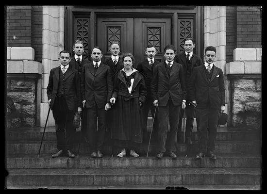 Eight men, one woman, with canes on steps of Carnegie Library