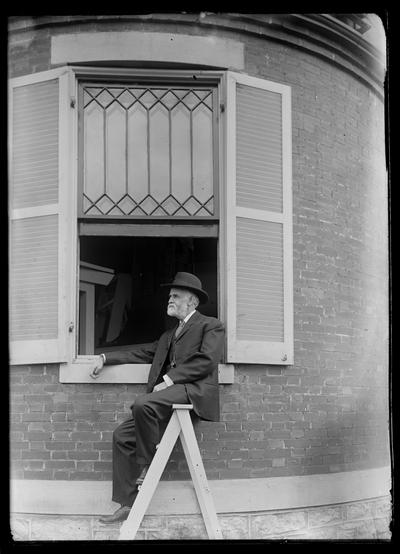 Professor J.G. White on ladder by window of home