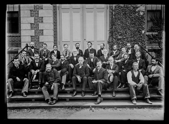 University of Kentucky faculty group, 1895-1896, seated, hats off, on steps of Administration Building (Main Building)