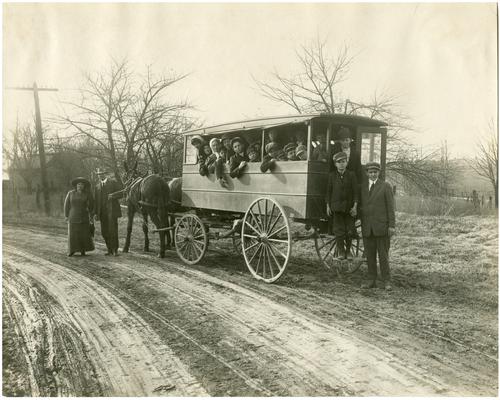 Group portrait of Greendale students riding in a horse-drawn wagon. Nannie Faulconer (1865?-1940) and the driver, Sam Brooks, stand along side