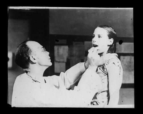 Dr. Caywood administers a dental examination to a student