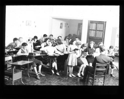 Junior High school students in classroom with girl reading aloud