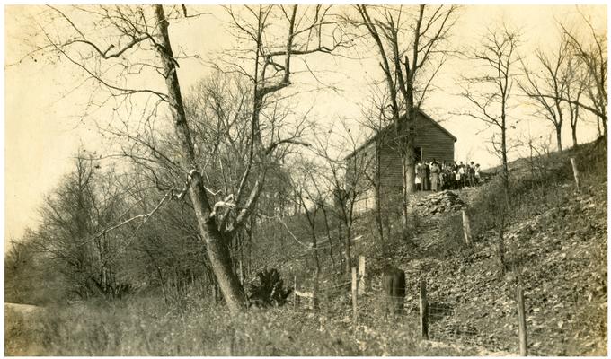 Group portrait, from a distance, of Little Georgetown students and Nannie Faulconer (1865?-1940) standing in front of the school house. Handwritten on verso, Picturesque Little Georgetown a colored school in the heart of the Blue Grass. This old building is on the banks of South Elkhorn Creek, Fayette County, Ky. This poor school is praying to grow into a fine colored school like Maddoxtown in the same county.(Three copies)