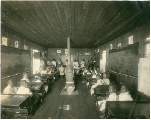 Group portrait of Little Georgetown students sitting at their desks and Nannie Faulconer (1865?-1940) standing in the doorway. Handwritten on verso, Little Georgetown, 5 copies. (Two copies)