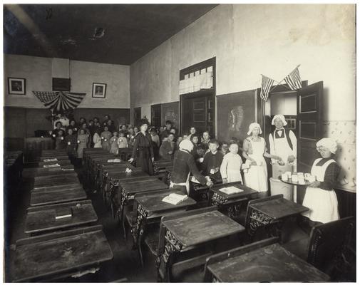 Loradale students receiving soup in the classroom with their teacher, Audrey Burgin Hawkins. Handwritten on verso, Loradale Hot Lunch Service. (Five copies)