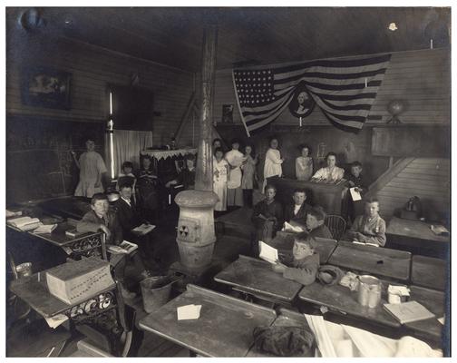 Group portrait of Old Brighton students sitting at their desks with their teacher, Miss Millie Mae Watson