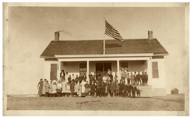 Group portrait of Rose Hill students and Nannie Faulconer (1865?-1940) standing in front of the school house. Handwritten on verso, 