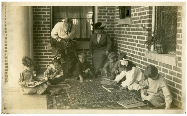 Picadome Montessori class doing work with Nannie Faulconer (1865?-1940) and Belle McCubbing. Handwritten on verso, Class in Montessori at Picadome rural school No. 20, Fayette County, Ky. (Three copies)