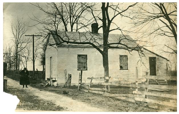 A man walking around an unidentified school house which was abandoned for consolidated schools (Two copies)