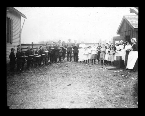 Students in soup line outside Cave Springs School with Miss Rose Wurtele, teacher