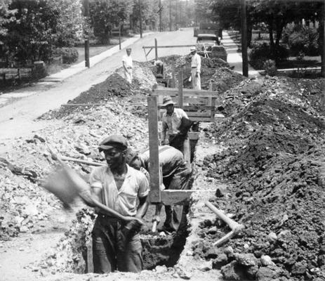 Project #2718, Master Project #3157 District 3: Project #2718, now consolidated under Master Project #3157, is the construction of sanitary sewers for various streets in Paris, KY. Workmen excavating a trench for installation of an 8-inch vitrified pipe in Lilleston Avenue. View photographed July 29, 1936