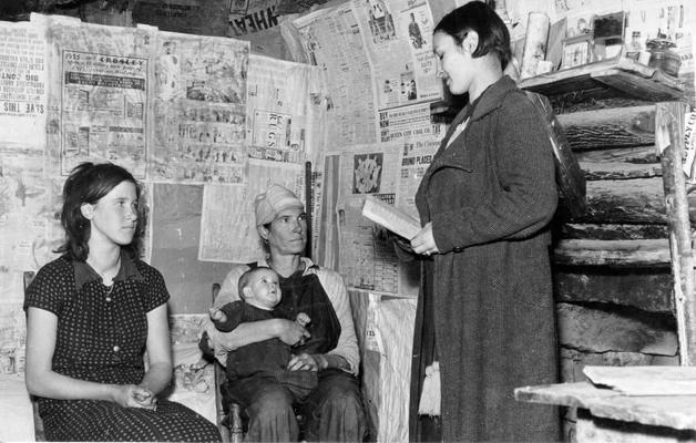 Project #0-73-9967 State-wide Education Project. Literacy teacher visits mountain home. This family, illiterate before visits by the teacher, is now able to do a little reading and spelling. The mother of the family is the one wearing overalls. The literacy work is part of the state-wide education project