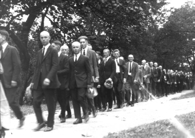 Students in procession, several with heads shaved