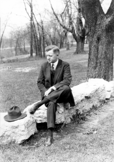 Unidentified man seated on stone wall