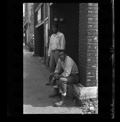 Two African-American men by wall