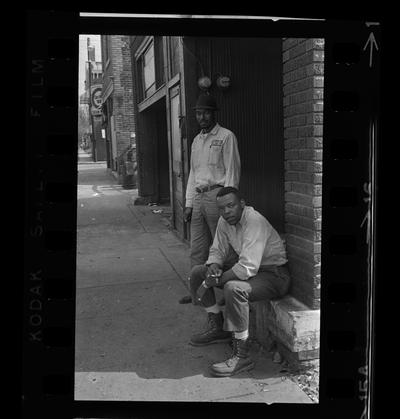 Two African-American men by wall