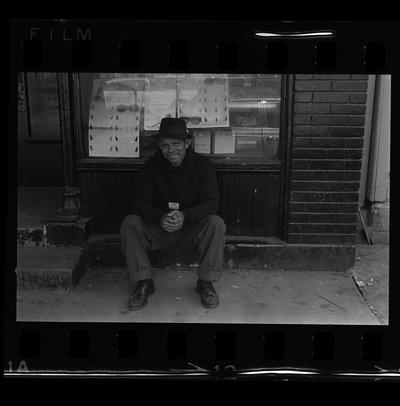 African-American man sitting, Three African-American men standing in alley, Two African-American men by wall