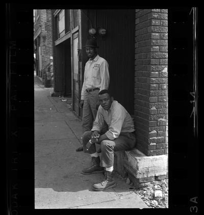 African-American man sitting, Three African-American men standing in alley, Two African-American men by wall