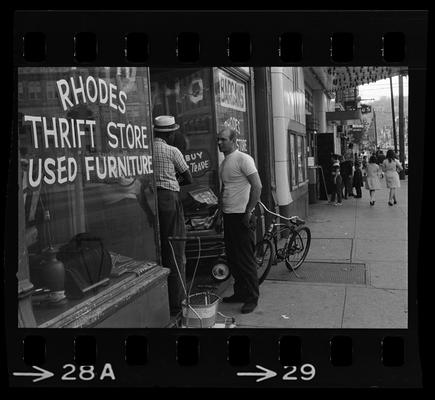 Two men in front of Rhodes Thrift Store and Used Furniture