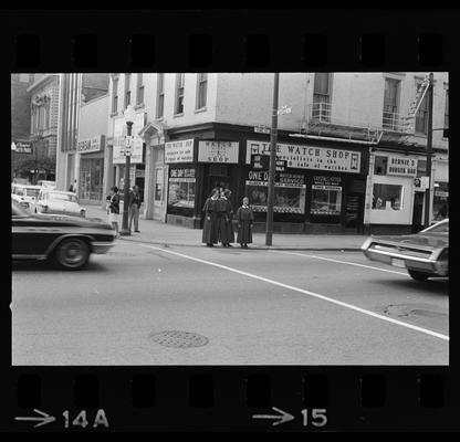 Woman throwing trash away, Nuns standing on a corner, Man standing on a corner