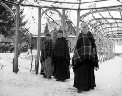 3 women walking outside in the snow with blankets wrapped around them