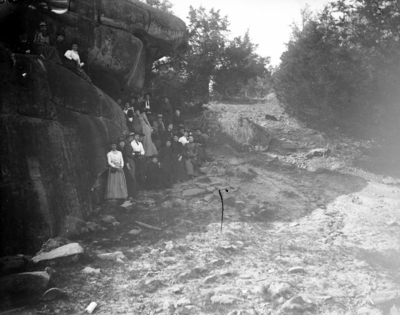 a group of people posing for a picture at a very large rock formation