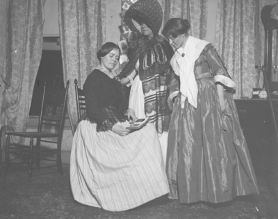 3 women looking at a book, sitting in a dorm room