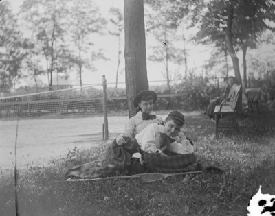 2 women sitting on a blanket together outside