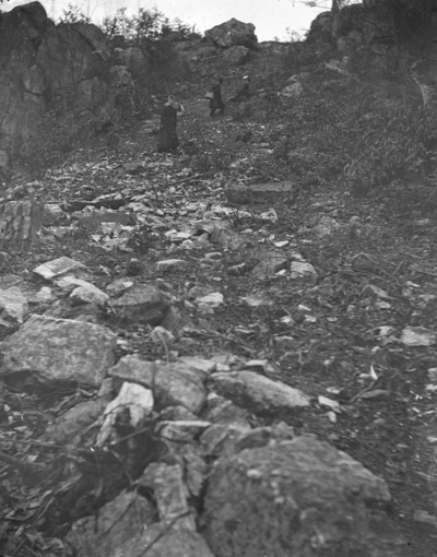 3 people walking up a rocky hillside