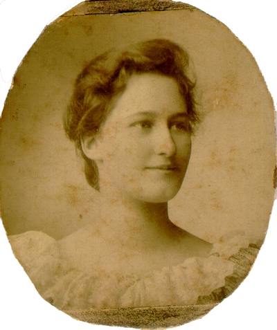 Young woman with brown hair wearing a dress with no neck and white lace at top, mounted on oval card