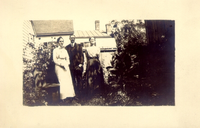 Children of J.K. Lyle: Lizzie A. Lyle (left), Charles N. Lyle (center), Helen Lyle (right); standing in garden between home and barn