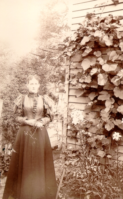 Helen Lyle standing in garden next to house; variant of #198