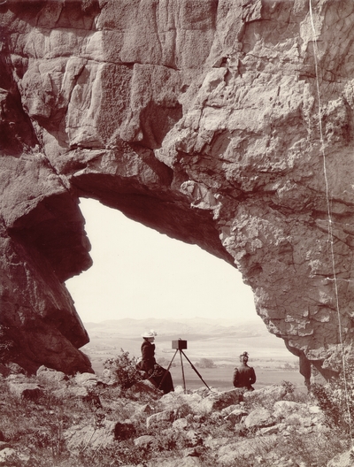 Two women with a camera looking out over a desert landscape