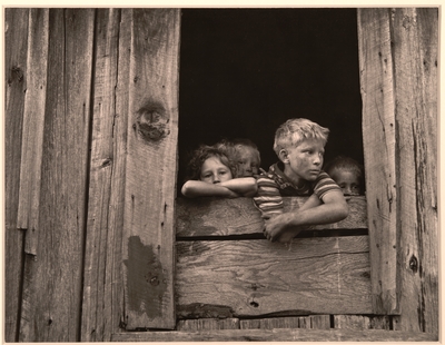 Children of miners look out the kitchen window of the Monroe Jones house.  The windows have no panes, the door frames have no doors; old quilts and boxes are used during the winter for protection.  Four Mile, Bell County, KY. 9/4/46