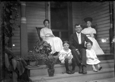 Family sitting on a porch;                          Adams Negative handwritten on envelope