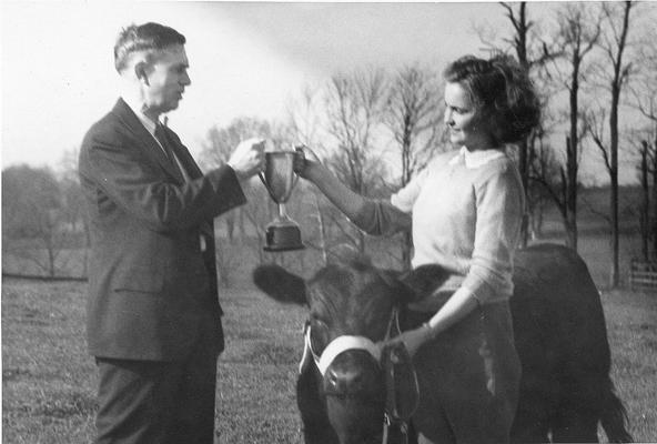 Young woman with trophy and prized cow