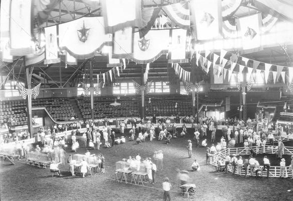 People in a large arena viewing and judging animals