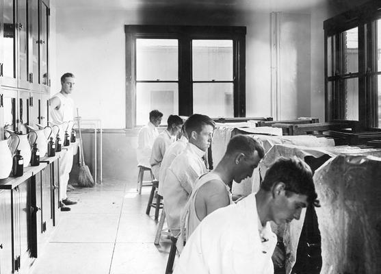 Students milking cows in a milking parlor