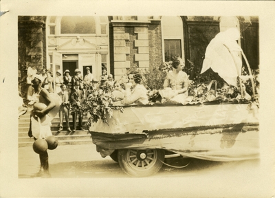 Women on a parade float with spectators in the background May 2, 1930