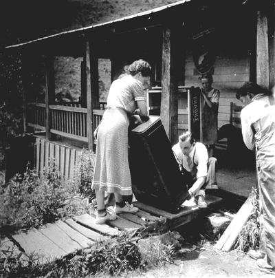 Man and woman inspecting new radio on wooden sidewalk, outside of mountain home