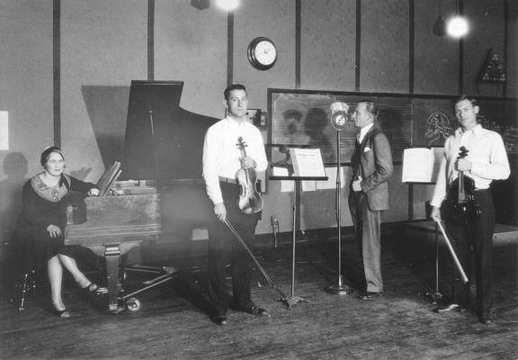 Musicians (one woman, two men) and announcer at WHAS/UK studio: group preparing to perform 