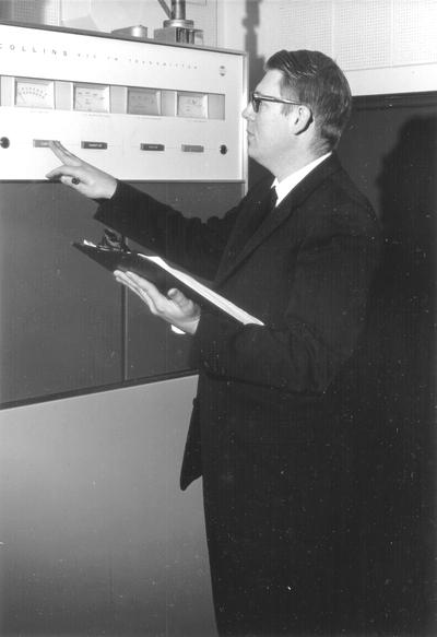 Unidentified man taking meter reading for station transmitter