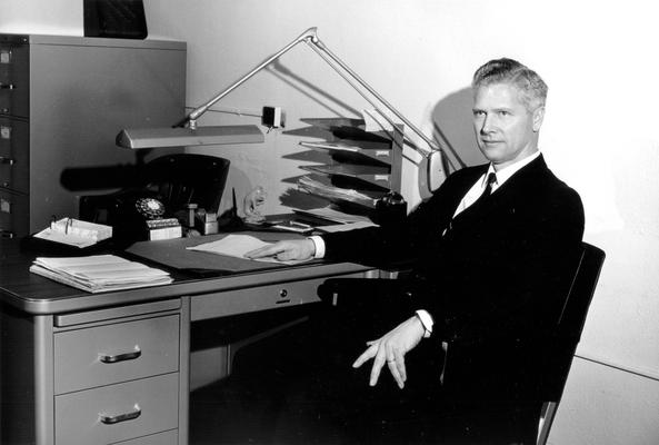 Stu Hallock sitting at desk with back to the wall