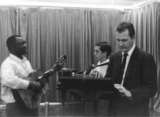 African-American Man playing guitar with young man, man at podium