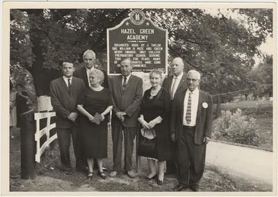 A group of five men and three women standing in front of a plaque (August 13, 1961):                          Hazel Green Academy / Dedicated 1800 by J. Taylor Day, William D. Mize and Green Berry Swango. Only College Preparatory School This Area ForYears