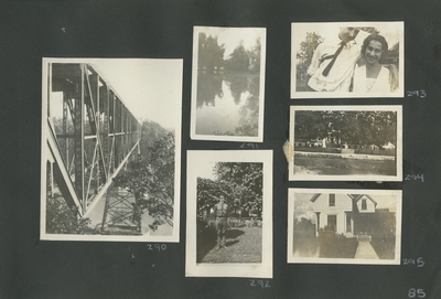 a bridge over water; water and trees; a man in uniform standing in the yard; a fence and building in the distance; exterior of a house