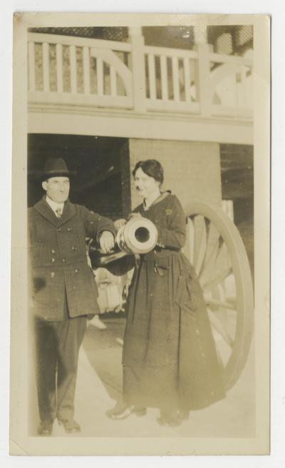 Unidentified man and woman standing next to a cannon