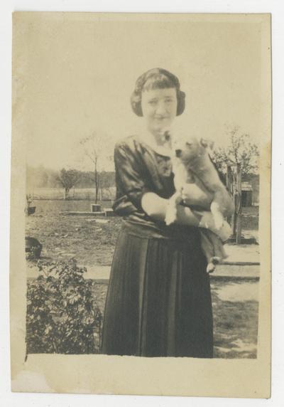 Unidentified young woman holding a small dog